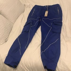 royal blue pants multiple zip up pockets straps at the bottom of the pants